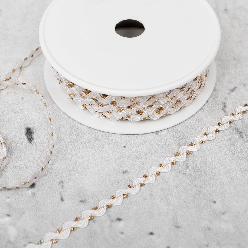 Ozdobna taśma typu zyg-zag w kolorze biało-złotym.