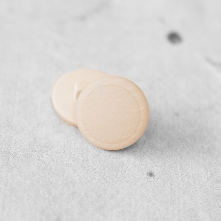 Plastikowy guzik na stopce, o średnicy 1,8 cm.